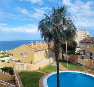 a villa with a palm tree and a swimming pool at Apartamento muy cerca del mar. in Arenales del Sol