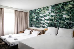 une chambre d'hôtel avec 2 lits et un tableau mural dans l'établissement Novotel Saint Avold, à Saint-Avold