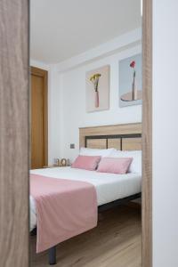 Un dormitorio con una cama grande con almohadas rosas. en Alojamientos Rías Baixas-Casa Lisi-Ribeira, en Ribeira