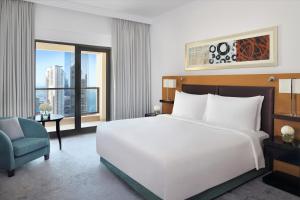 - une chambre avec un grand lit blanc et une chaise bleue dans l'établissement Mövenpick Hotel Jumeirah Beach, à Dubaï