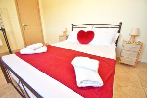 a bed with a red heart on top of it at Nikolas Beach House in Mesongi