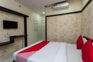 a bedroom with a bed with red pillows and a tv at OYO Sun Palace in Jabalpur