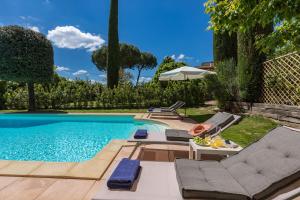 uma piscina com duas espreguiçadeiras e uma mesa com um prato de comida em Villa Joy 6, Emma Villas em Foiano della Chiana