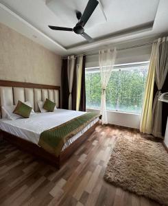 een slaapkamer met een bed en een groot raam bij Jungle Fowl Resort in Dehradun