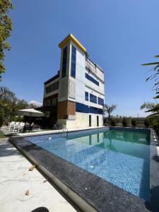 een gebouw met een zwembad voor een gebouw bij Jungle Fowl Resort in Dehradun
