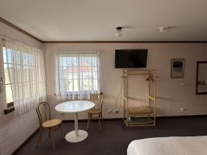 a room with a table and chairs and a tv at Shaen Street Motel in Port Lincoln
