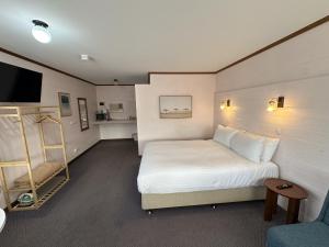 a bedroom with a white bed and a tv and a chair at Shaen Street Motel in Port Lincoln