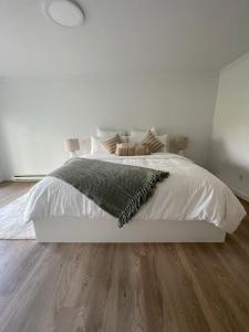 a bedroom with a white bed and wooden floors at 43 Ave Farm House Langley in Aldergrove