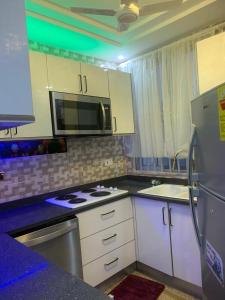 a kitchen with white cabinets and a stove and a microwave at Mr Nti’s Lodging House in Oheneba Kokobin