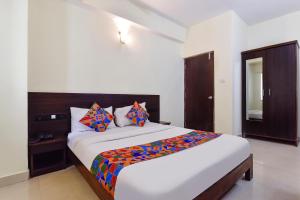 a bedroom with a large white bed with colorful pillows at FabExpress Clausil Inn in Taleigao