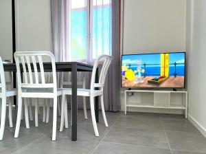 a dining room table with white chairs and a tv at Appartamenti Vanin Ca' di Valle in Cavallino-Treporti