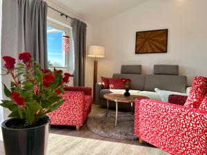 a living room with red chairs and a couch at Haus Concordia 2 Lieblingsort in Thiessow