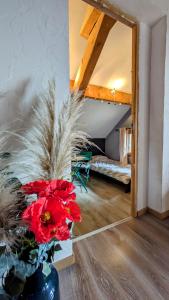 a vase with red flowers in a room with a bed at Au bon endroit -- Chambre chez l'habitant -- Via Rhona in Jonzier-Épagny +6 photos