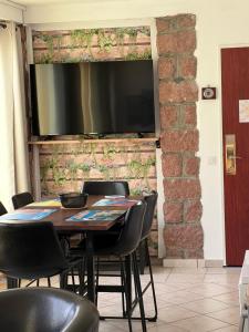 uma mesa com cadeiras e uma televisão numa parede de tijolos em Residence Appartement le Porto em Porto Ota