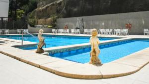 dwa posągi przed basenem w obiekcie Hotel Acapulco Benidorm w mieście Benidorm