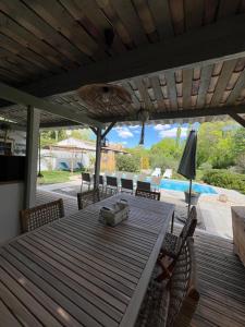a wooden table with chairs and an umbrella on a patio at La Belle Rivière in Salernes