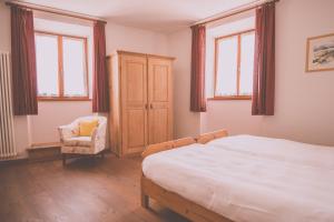 um quarto com uma cama, uma cadeira e janelas em Agritur Ca' de Mel em Fiavè