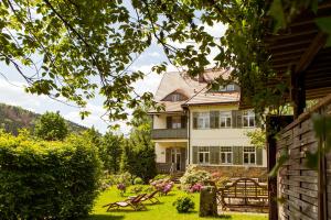 ein Haus mit einem Hof mit Bänken davor in der Unterkunft Villa Elbufer in Bad Schandau