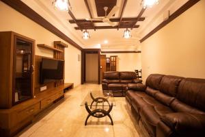 a living room with a leather couch and a television at Luxury Hill Top Apartment by EWA Properties in Mangalore
