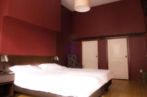 a bedroom with a white bed and red walls at Hotel Bertram in Bredevoort