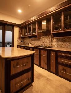 a large kitchen with wooden cabinets and a counter top at Luxury Hill Top Apartment by EWA Properties in Mangalore