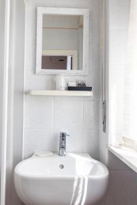 a white bathroom with a sink and a mirror at Hotel Moranna in Lido di Camaiore
