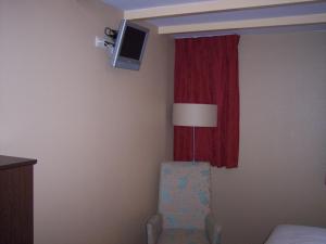 a room with a chair and a window with a tv at Hotel Bertram in Bredevoort