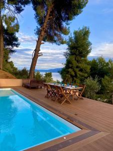 una piscina con tavolo e sedie accanto a una terrazza in legno di Askalosia villa a Agios Georgios