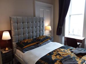 a bedroom with a large bed with a padded headboard at IVY- Braveheart Guest House in Edinburgh +65 photos
