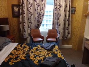 sypialnia z 2 krzesłami, łóżkiem i oknem w obiekcie IVY- Braveheart Guest House w Edynburgu