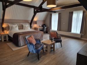 een slaapkamer met een bed en 2 stoelen en een tafel bij Herberg Welgelegen in Katwijk