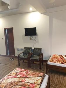 a room with two beds and two chairs and a flat screen tv at Rehan Hotel in Quetta