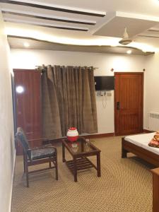 ein Wohnzimmer mit einem Bett, einem Tisch und einem Stuhl in der Unterkunft Rehan Hotel in Quetta