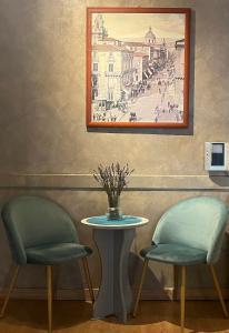 duas cadeiras e uma mesa com uma foto na parede em B&B Stesicoro InHabit - GuestHouse City Center em Catânia