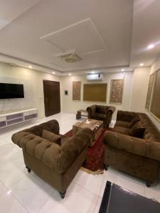 uma sala de estar com sofás e uma televisão de ecrã plano em C Suites em Lahore