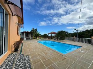 a swimming pool in front of a house at Le Volcan - Piscine - DODOTERLA in Sainte-Rose
