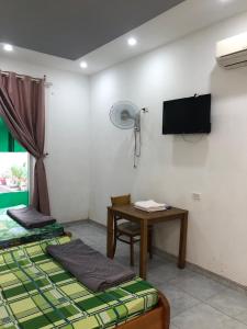 a room with two beds and a table and a fan at Nhà Nghỉ Minh Thảo in Chơn Thành