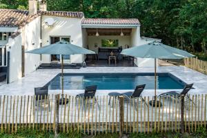 Montazeau的住宿－Domaine du Pré de l'étang，房屋旁的游泳池配有椅子和遮阳伞