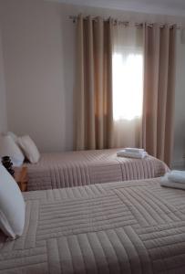 2 bedden in een slaapkamer met een raam bij Vicky's Guesthouse in Kavos