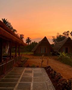 um pôr-do-sol sobre uma aldeia com casas e um caminho em Tropical Hampi em Hampi