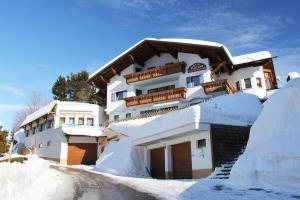 a building covered in snow next to a road at Appartements Platzis in Schruns-Tschagguns
