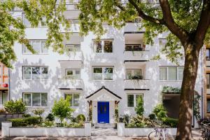 a white apartment building with a blue door at Apartmenthaus Hamburg Les Jardins in Hamburg