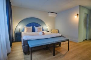 Hotel Halbert في خرونينغن: غرفة نوم بسرير كبير ومقعد بلو