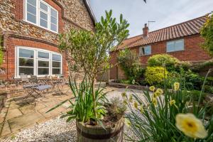 einen Garten vor einem Backsteinhaus in der Unterkunft Peony Cottage in Helhoughton
