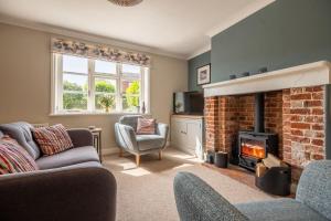 ein Wohnzimmer mit einem gemauerten Kamin und Stühlen in der Unterkunft Peony Cottage in Helhoughton