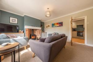 ein Wohnzimmer mit Couch und Kamin in der Unterkunft Peony Cottage in Helhoughton