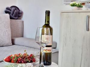 a bottle of wine and a bowl of strawberries on a table at Kućica na Drini "JAZ" in Višegrad