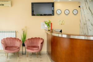 a waiting room with two pink chairs and a tv at Lucky Hotel in Veliko Tŭrnovo