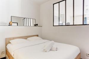a bedroom with a bed with white sheets and a mirror at Le Cozy - Saint Cyr in Saint-Cyr-lʼÉcole