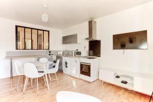 a kitchen with white appliances and a table and chairs at Le Cozy - Saint Cyr in Saint-Cyr-lʼÉcole